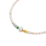 Pearl beaded necklace with green and gold jade beads on a white background, close-up
