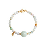 Bracelet with white and green jade beads and gold accents on a white background, top view