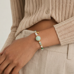 Person wearing a jade beaded bracelet on a neutral background