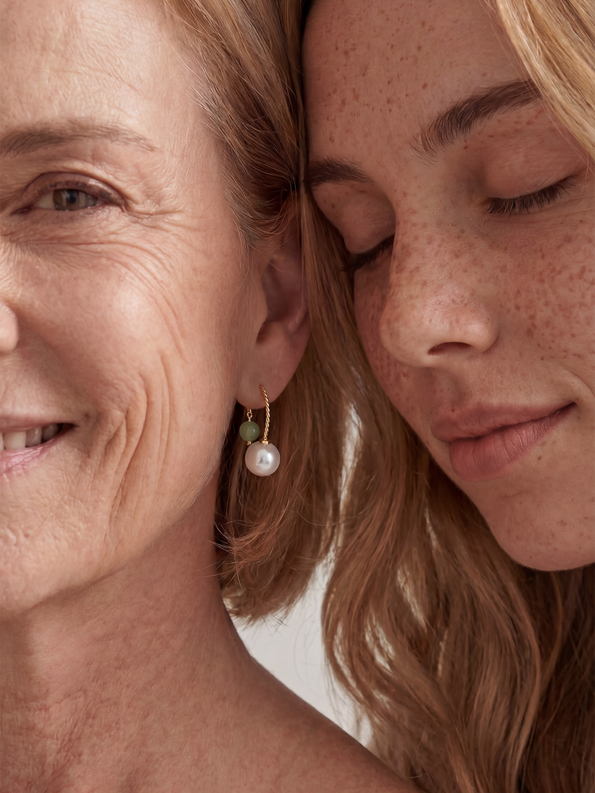 Close-up of two women with a focus on one wearing pearl earrings.