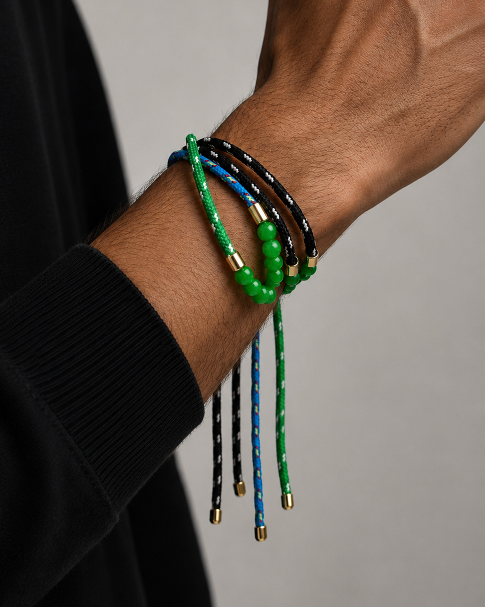 Close-up of a wrist wearing multiple colorful bracelets on a neutral background