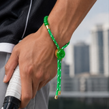 Person holding a tennis racket with a green bracelet on a blurred cityscape background
