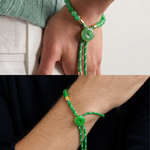 Close-up of a green bracelet with button-like beads on a wrist against a neutral background.