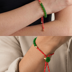 Close-up of a wrist wearing a red and green beaded bracelet with gold accents.