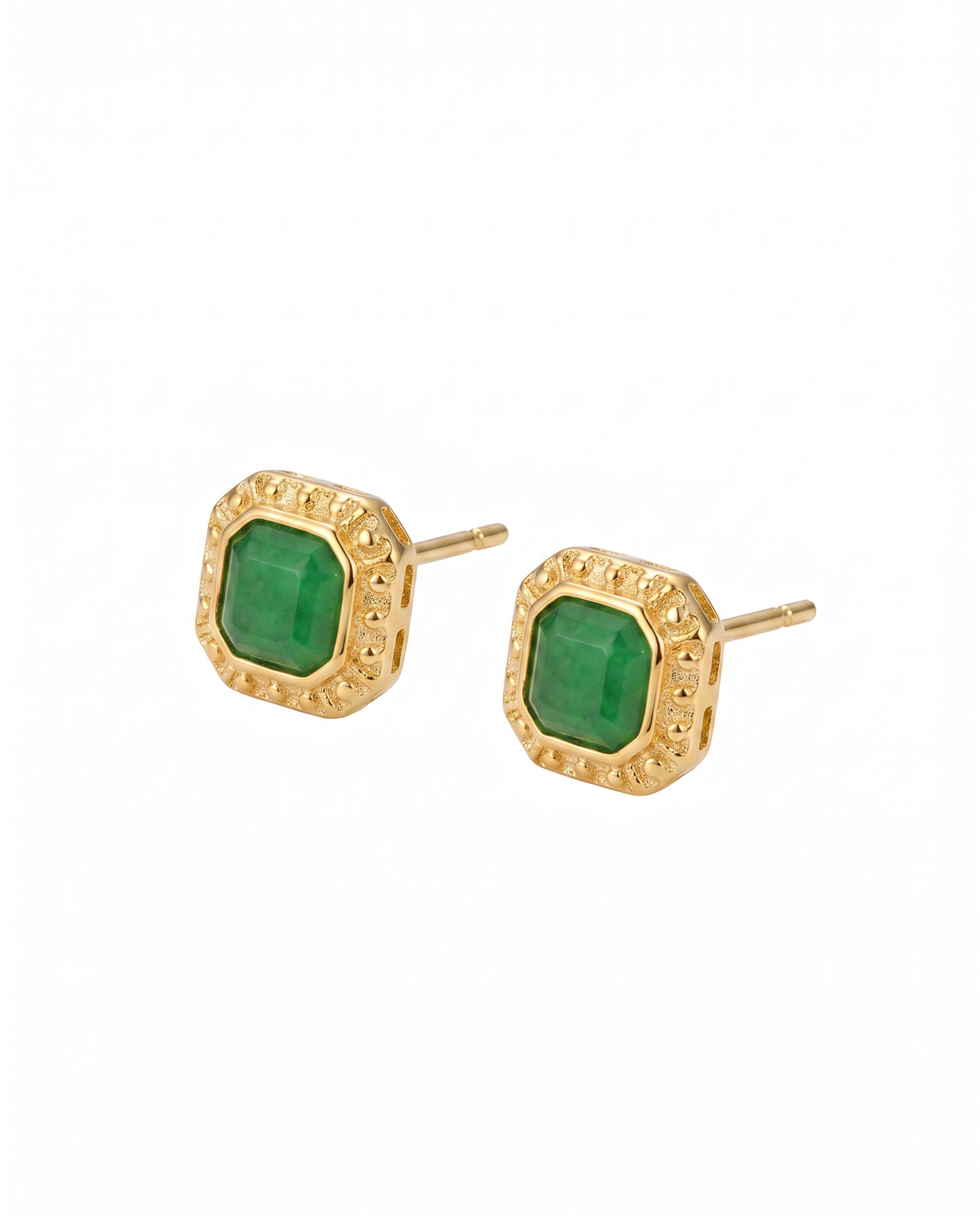 Gold earrings with green gemstones on a white background