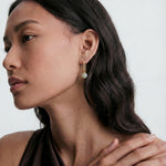 Woman wearing jade earrings with a neutral background