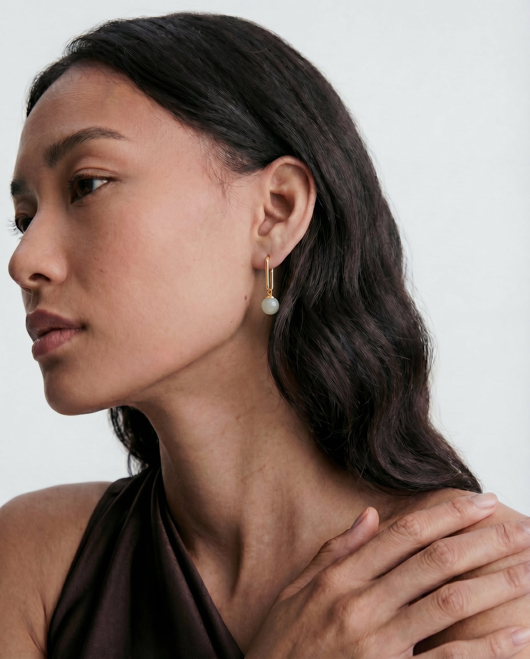 Woman wearing jade earrings with a neutral background