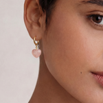 Close-up of a person wearing an earring with a pink heart-shaped charm.