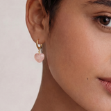 Close-up of a person wearing an earring with a pink heart-shaped charm.