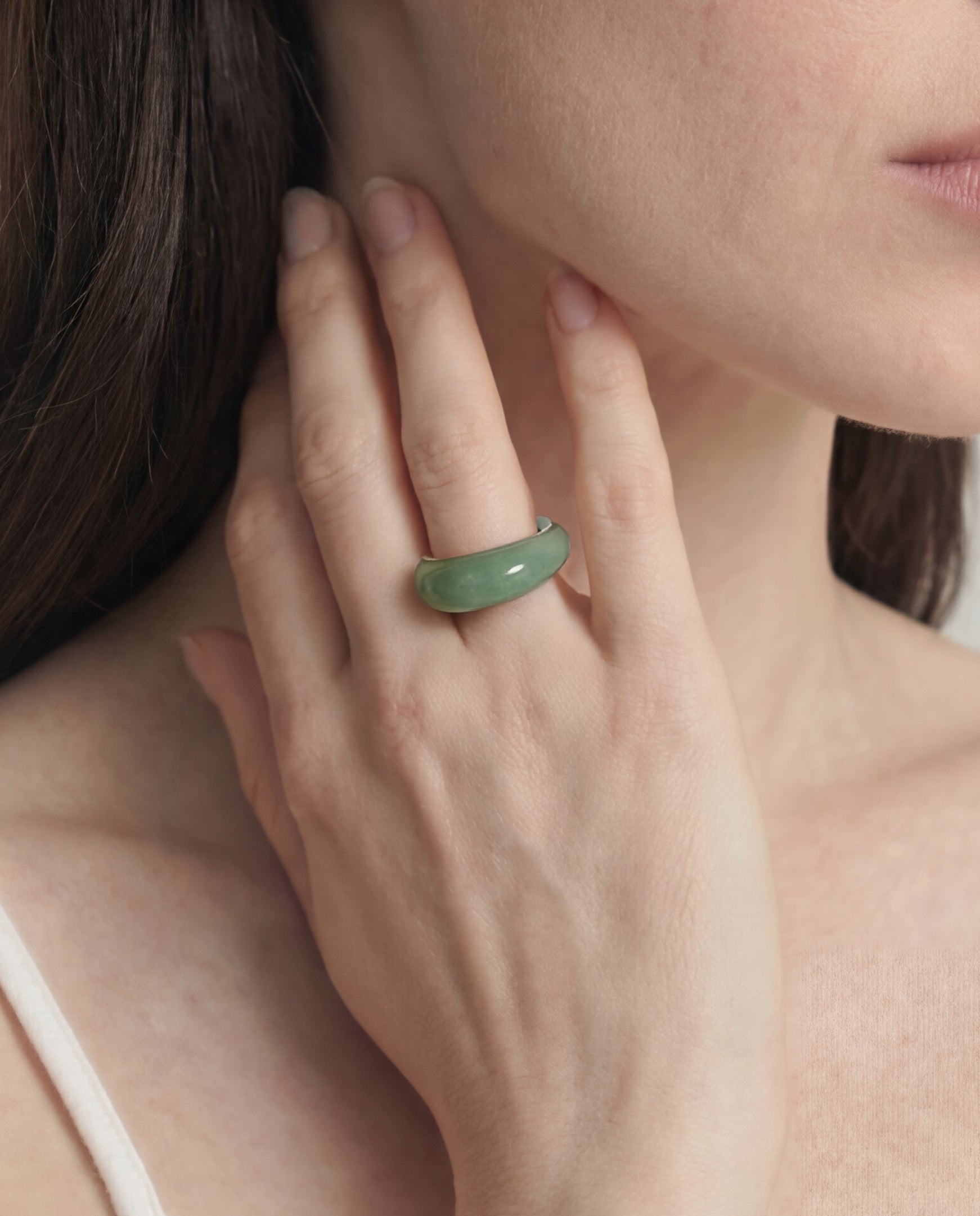 Close-up of a hand wearing a green ring with a blurred background