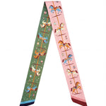 A green and pink scarf with carousel designs on a white background
