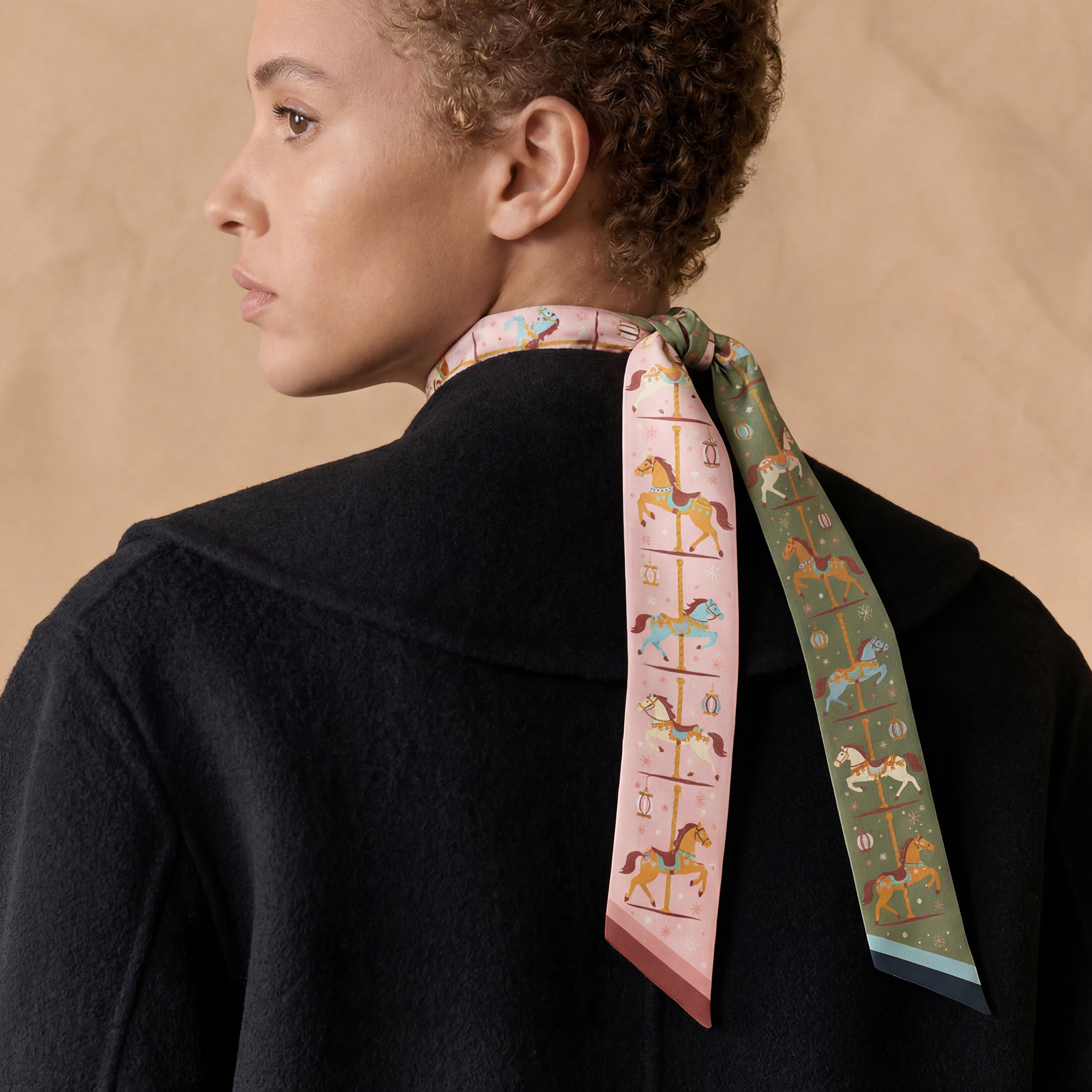 Person wearing a green and pink scarf with carousel design on a beige background